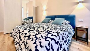 Une chambre à coucher comprenant un lit, une table de chevet, un miroir et un luminaire fixé au mur.