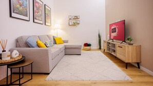 Un salon moderne avec un canapé, un téléviseur, un meuble en bois et des œuvres d’art encadrées accrochées au mur.