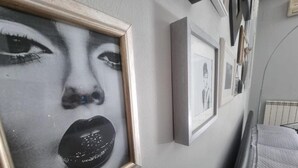 Un dormitorio con cama, una mesita de noche y un estante con marcos.