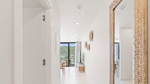 A corridor with a view to a balcony, white walls, and a large mirror with a textured frame. - B254 - Cozy Apartment in the Heart of Simpson Bay (Sint Maarten)