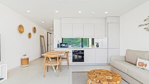 A modern kitchen with white cabinets, a dining area with a wooden table and chairs, and a living room with a beige sofa and a round wooden coffee table. - B254 - Cozy Apartment in the Heart of Simpson Bay (Sint Maarten)