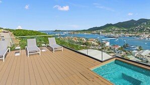 A wooden deck with lounge chairs and a pool overlooking a marina and coastal town. - B254 - Cozy Apartment in the Heart of Simpson Bay (Sint Maarten)