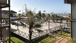 Ett semesterhotell vid stranden med byggnader som har tak av halmtak, en asfalterad gångväg och palmer.