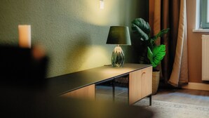 A modern living room with a sleek console table, a floor lamp, and a potted plant. - Luga Homes - Karli (Leipzig)