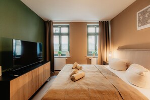 A hotel room with a bed, a TV, a window, and a plant. - Luga Homes - Karli (Leipzig)