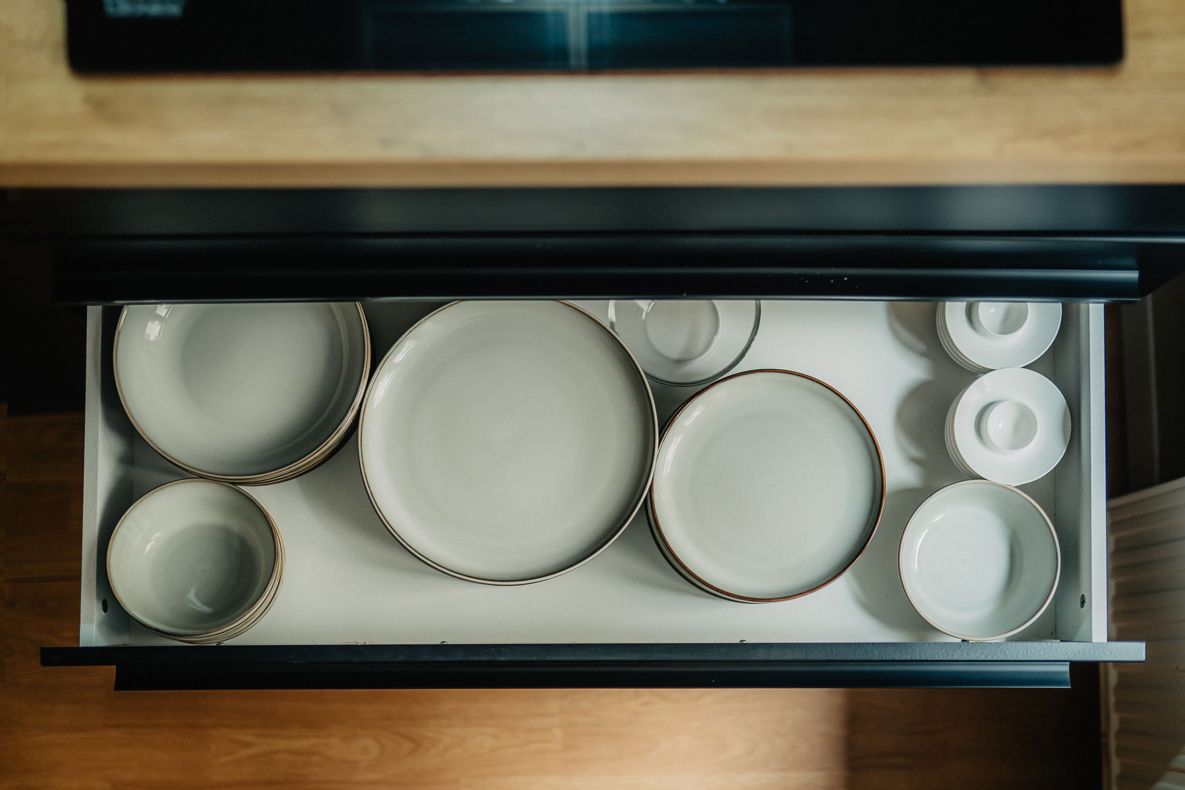A drawer with various plates and bowls, indicating a kitchen area.