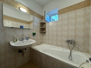 Une salle de bain avec un lavabo, un miroir et une baignoire.