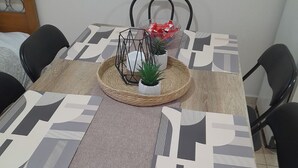 A dining table with a geometric patterned tablecloth, surrounded by black chairs, and a small potted plant on a woven tray. - Garden Paradise in Megalochori Trikala (Trikala)