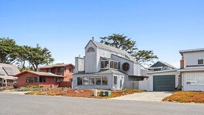 A modern two-story house with a garage, surrounded by a well-maintained lawn and trees. - Quick walk to the Beach
3 Bedrooms 1.5 Bath
 Sleeps 6 (Dillon Beach)