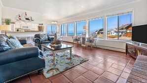 A spacious living room with a large window, a flat-screen TV, and a dining area. - Quick walk to the Beach
3 Bedrooms 1.5 Bath
 Sleeps 6 (Dillon Beach)