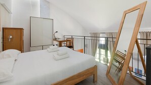 Un dormitorio con una cama de madera, un escritorio, una silla, un armario y un espejo grande.