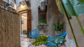 A narrow courtyard with a bamboo fence, a blue chair, and potted plants. - GuestHost - Ferrara Jungle Apartment (Ferrara)