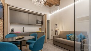 A modern kitchen with grey cabinets, a microwave, and a dining area with a round table and blue chairs. - GuestHost - Ferrara Jungle Apartment (Ferrara)
