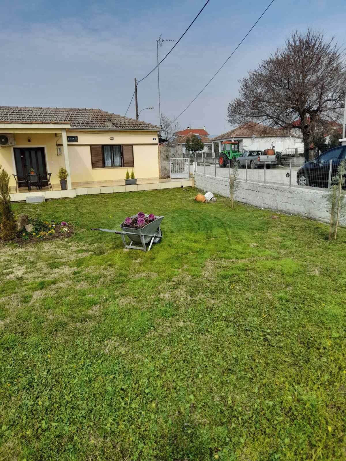 A residential area with a house, a lawn, a wheelbarrow, and a fence.