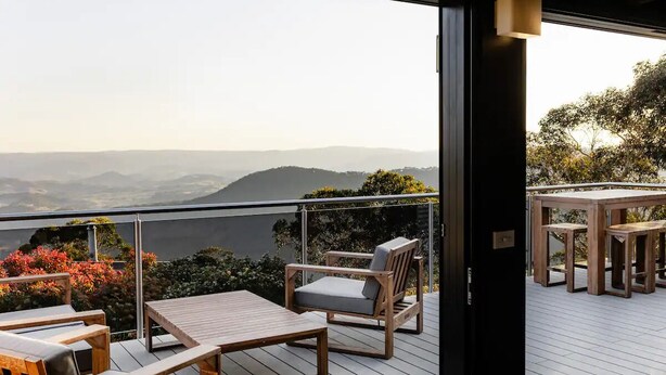 Un balcone con mobili in legno e vista su colline lontane.