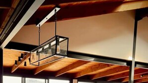 Una cucina moderna con una grande isola, travi in legno a soffitto e ampie finestre con vista sull'esterno.