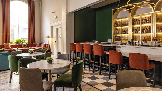 A bar area with a checkered floor, bar stools, and a bar counter with bottles. - Hotel Julian (San Francisco)