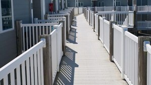 A row of beachside mobile homes with a wooden walkway and white railings. - MillionDollarView-Oceanfront 1BR-Updated! (Salter Path)
