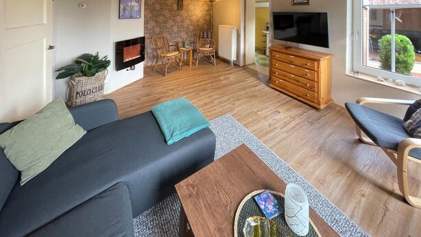 Un salon moderne avec un canapé, une table basse, un téléviseur et un meuble en bois.