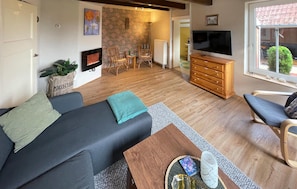 Un salon moderne avec un canapé, une table basse, un téléviseur et un meuble en bois.