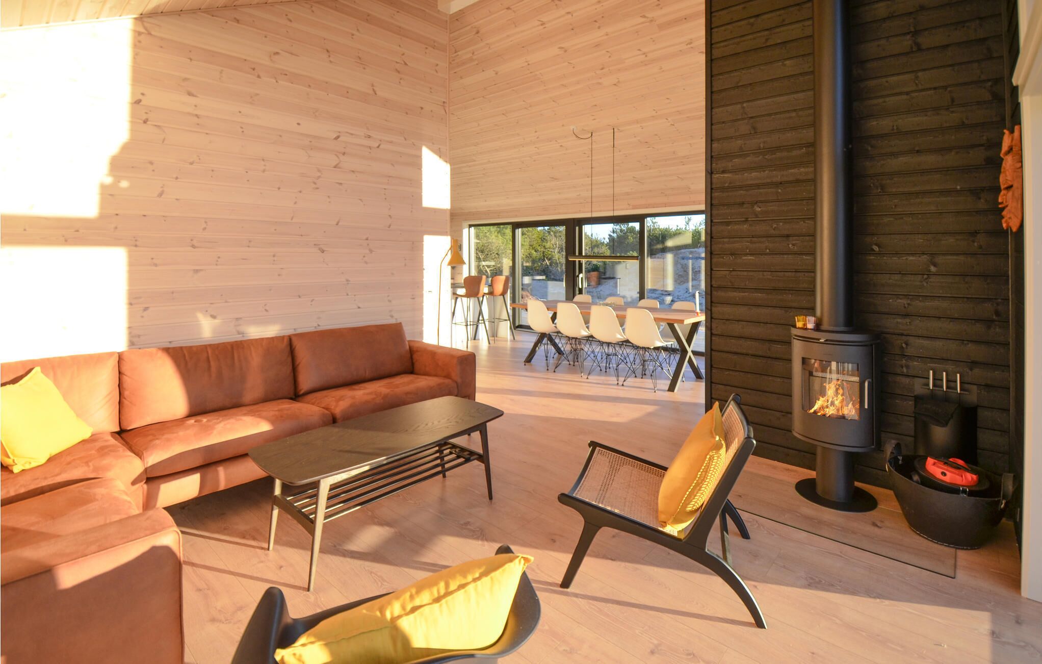 A modern interior with a leather sofa, a coffee table, and a chair with a yellow cushion. A fireplace is visible on the right side.