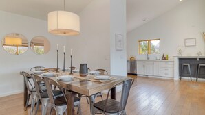 A dining area with a wooden table, metal chairs, and a hanging light fixture.