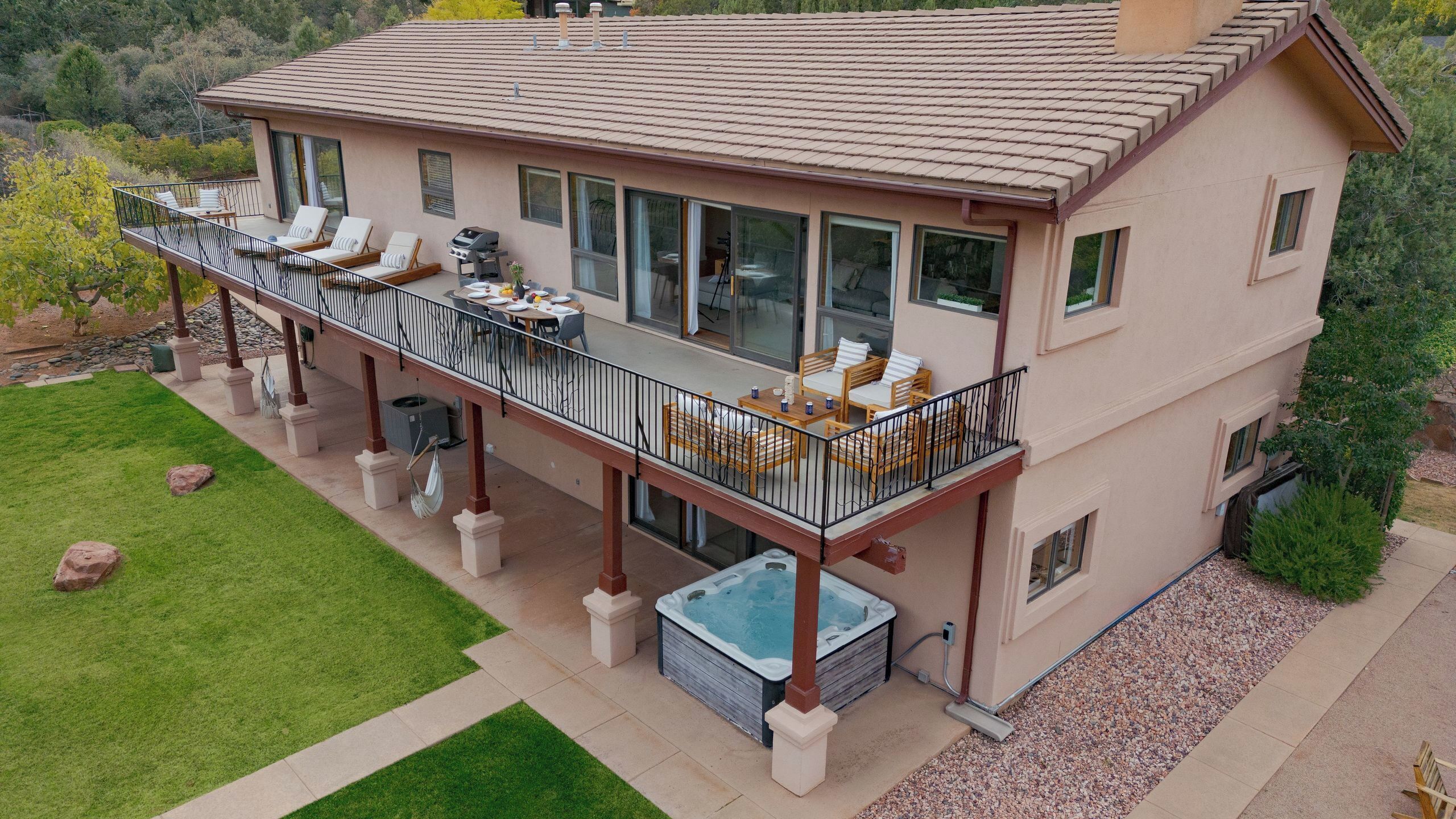 A two-story house with a balcony, outdoor seating, and a hot tub.