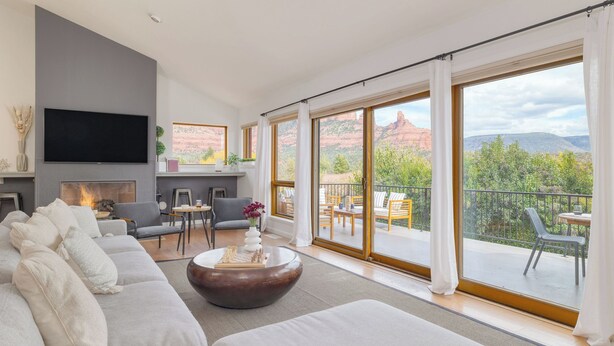A modern living room with a fireplace, a large TV, and a balcony with a scenic view.
