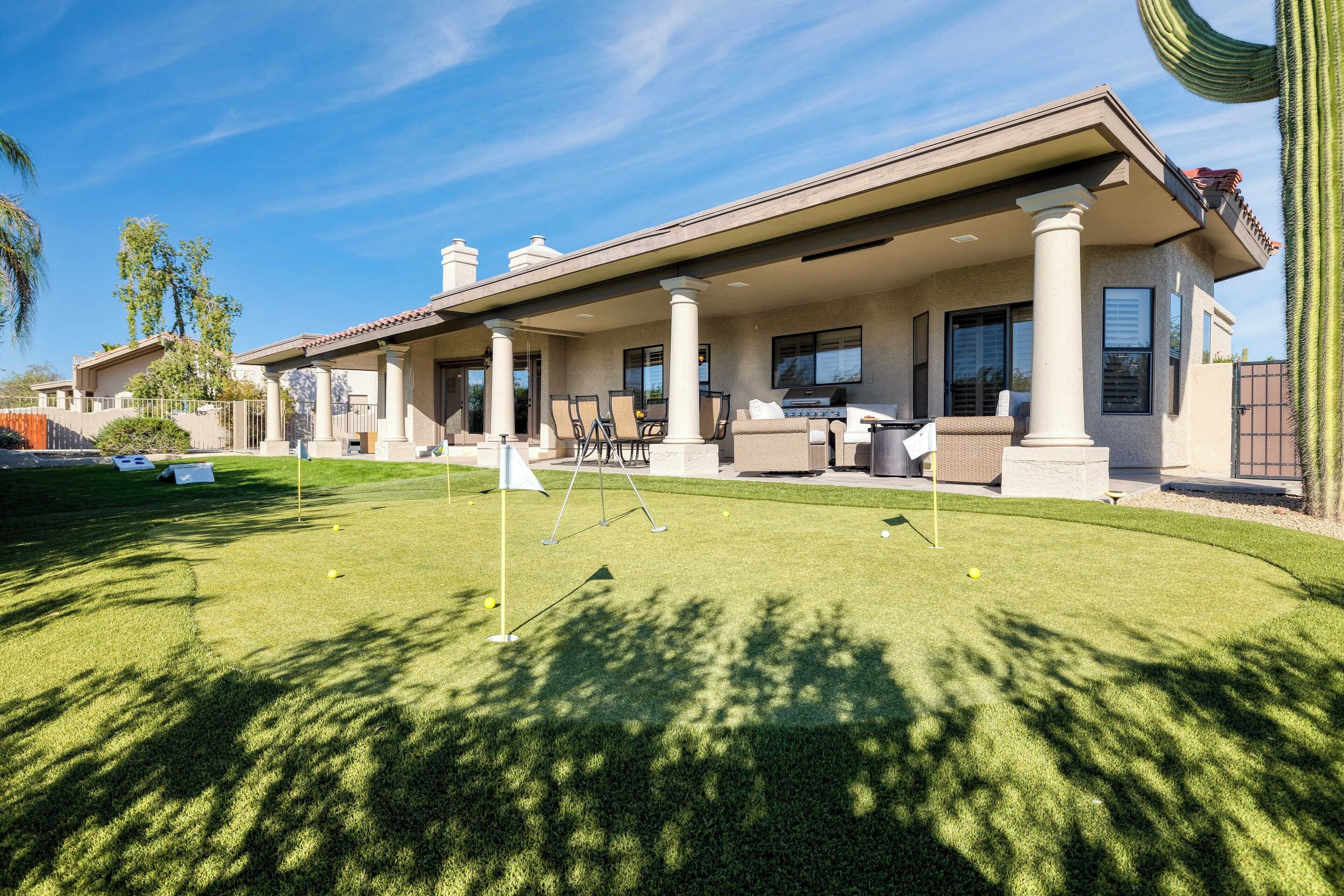 A house with a covered patio, outdoor seating, and a well-maintained lawn.