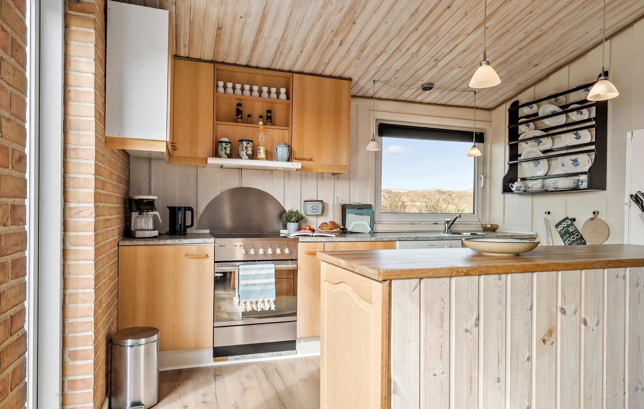 Una cocina con armarios de madera, una estufa, una cafetera y una ventana con vista al desierto.