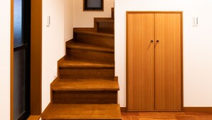Un escalier menant à un deuxième étage, une armoire en bois et une petite fenêtre.
