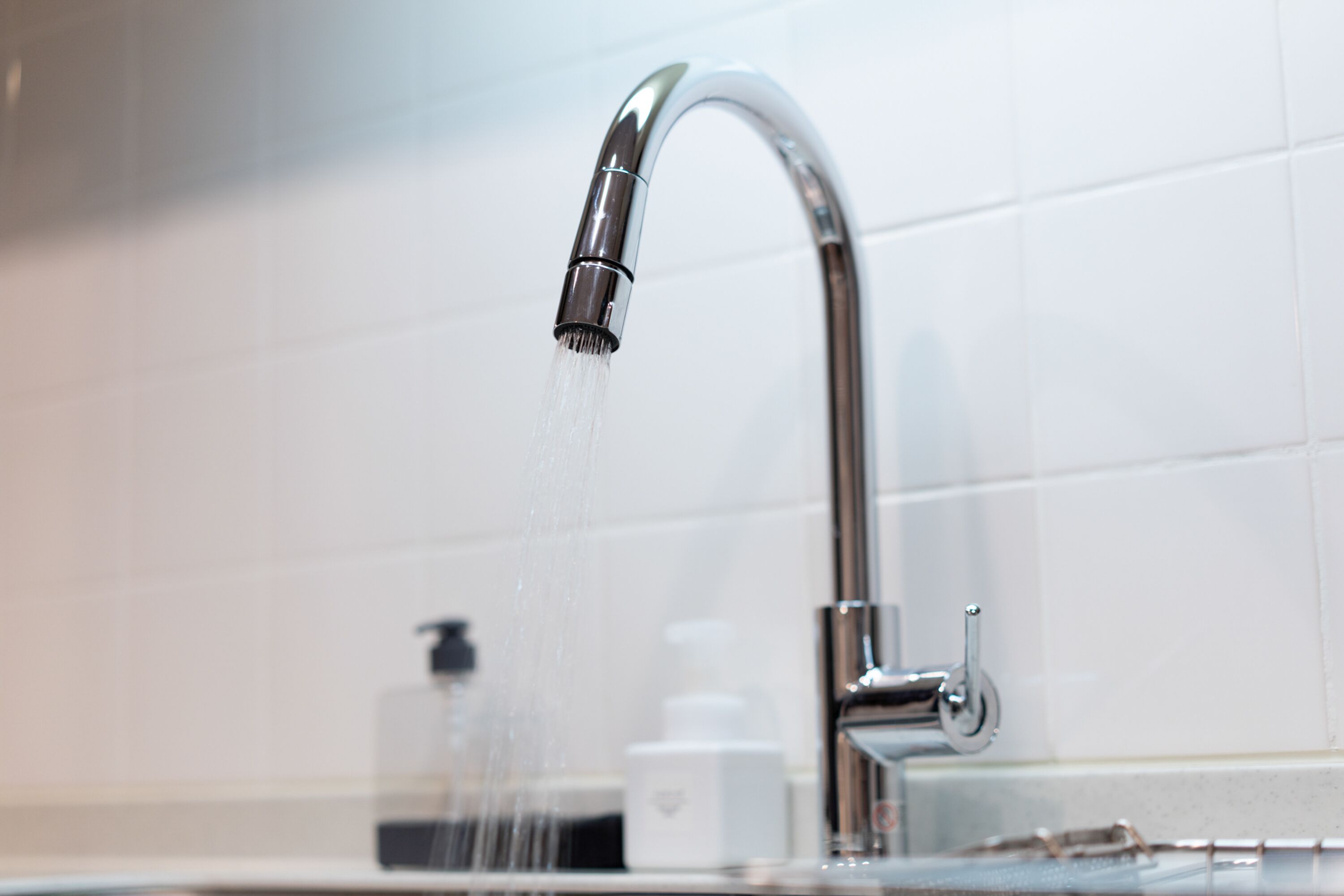 A modern bathroom with a chrome faucet and a soap dispenser on the counter.