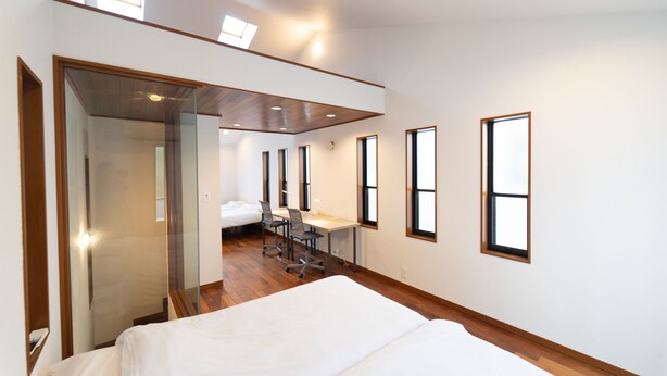 Une chambre d’hôtel moderne dotée d’un grand lit, d’un bureau et d’une cloison en verre.