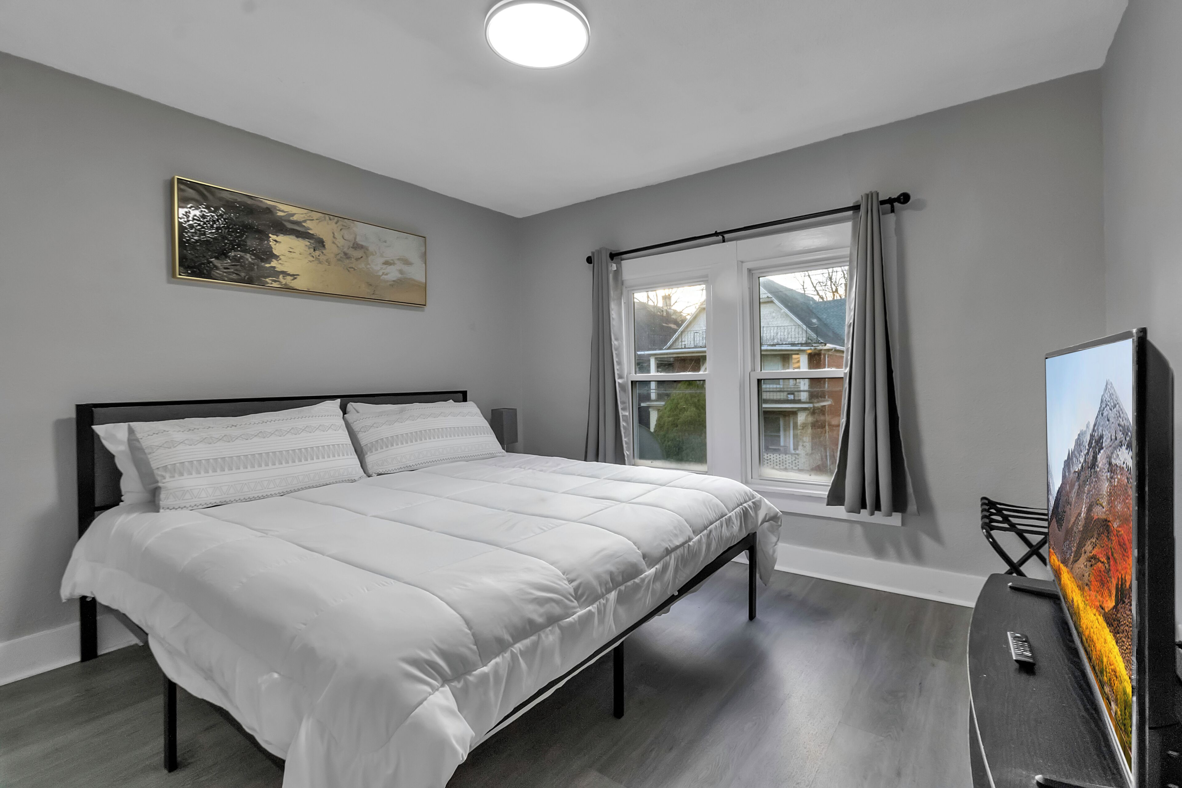 Une chambre moderne avec un grand lit, un téléviseur à écran plat et une fenêtre avec des rideaux.