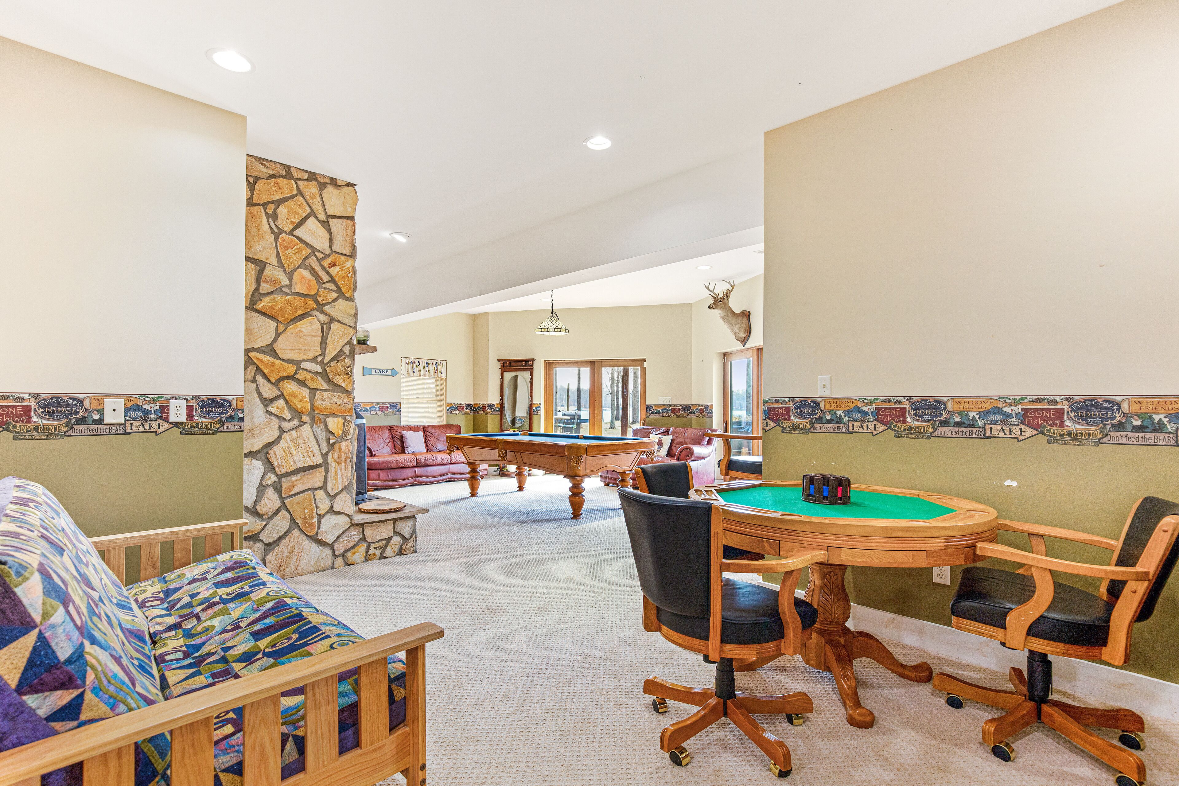 A spacious room with a pool table, a comfortable sofa, and a dining area with a wooden table and chairs.
