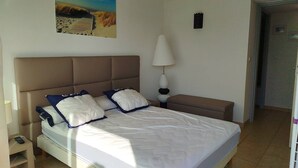 A bed with a headboard, a bedside lamp, and a painting of a beach scene. - Beautiful  flat with air conditioning, swimming pool and parking - 6REFC5 (SAINT CYPRIEN PLAGE)