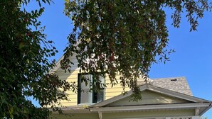 A two-story house with a porch, a front door, and a mailbox.