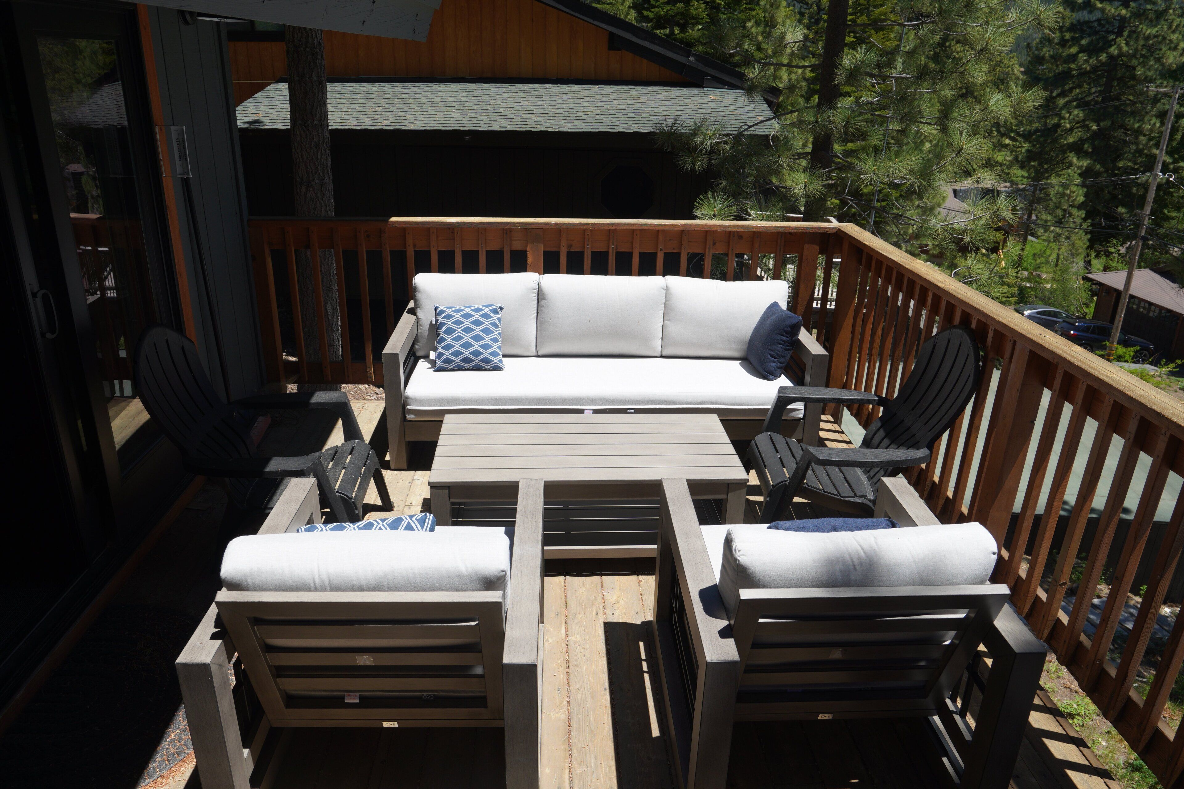 Une terrasse en bois avec un canapé et des fauteuils, une table et une rambarde.