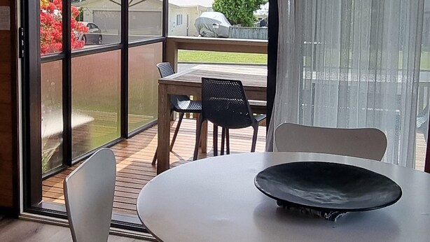 A modern dining area with a round table, two chairs, and a decorative ceiling light. - The Bach in old Wharewaka well located for a fabulous lake holiday. (Taupo)