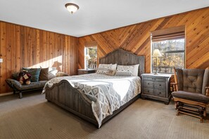 Ein Schlafzimmer mit einem großen Bett, einem Nachttisch, einem Sessel und einer Kommode.