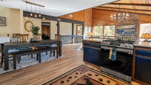 Une cuisine spacieuse dotée d’un grand îlot central, de planchers en bois et d’un mur décoratif en pierre.
