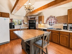 A kitchen with wooden cabinets, a brick backsplash, a central island, and a hanging light fixture.