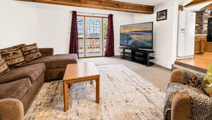 Ein Wohnzimmer mit einer Couch, einem Couchtisch und einem Flachbildfernseher.