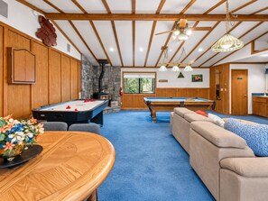 Una habitación con mesa de billar, mesa de snooker, un sofá y un armario de madera.