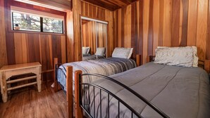 A wooden-paneled room with two beds, a small table, and a window. - Silver Rays - Walk to Lake/Village, Game Room, Pool Table, Air Hockey, BBQ (Big Bear Lake)