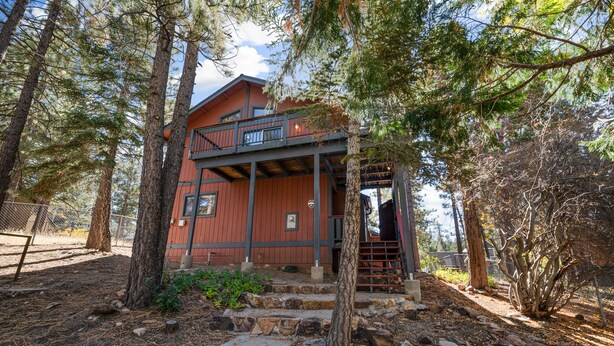 A rustic cabin with a balcony, surrounded by tall trees and a stone pathway. - Silver Rays - Walk to Lake/Village, Game Room, Pool Table, Air Hockey, BBQ (Big Bear Lake)