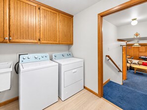 A laundry room with two white washing machines and wooden cabinets. - Silver Rays - Walk to Lake/Village, Game Room, Pool Table, Air Hockey, BBQ (Big Bear Lake)