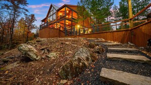 A wooden cabin with a balcony, surrounded by trees and a rocky landscape. - Creekside 6BR Retreat w/ UTV Trails & Hot Tub & Pet-Friendly (Broken Bow)