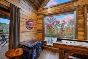 A wooden cabin interior with a large window, a wooden table, and a chair. - Creekside 6BR Retreat w/ UTV Trails & Hot Tub & Pet-Friendly (Broken Bow)