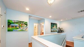 Un espace d’accueil avec un mur bleu clair, un plancher en bois et deux tableaux représentant des scènes tropicales.